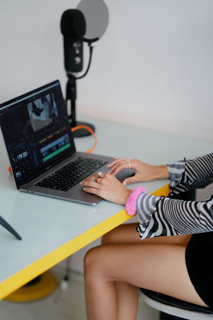 Young woman using laptop for video editing in a modern workspace.